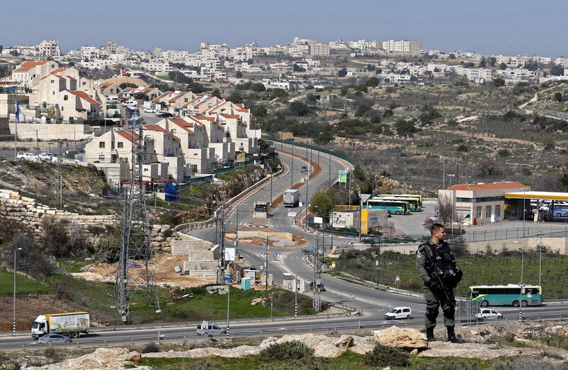 An Israeli soldier stands in front of the entrance to a Jewish-only settlement