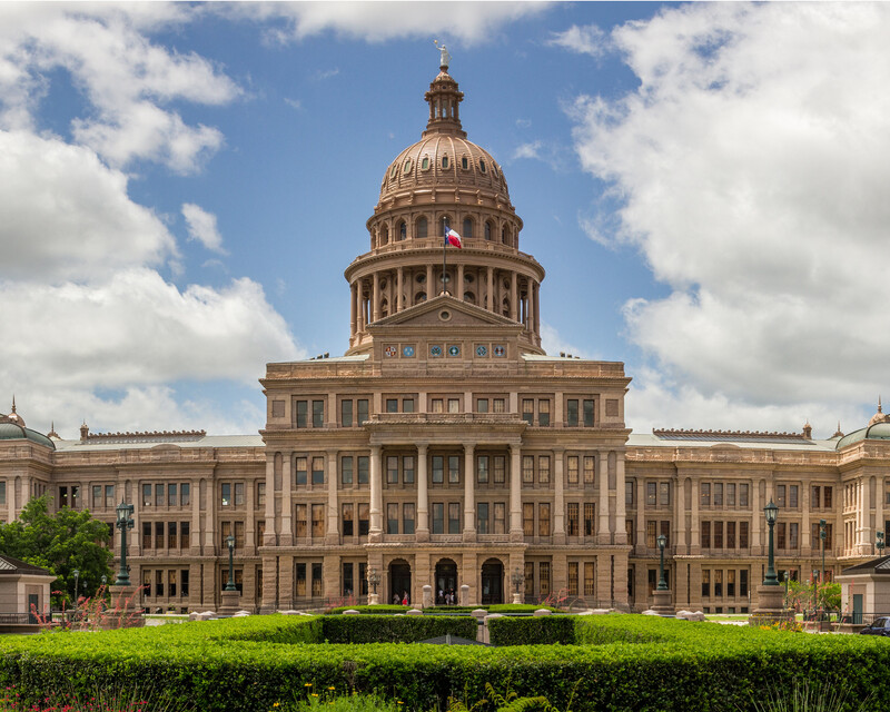 The Texas state capitol building with blue sky and clouds in the background.