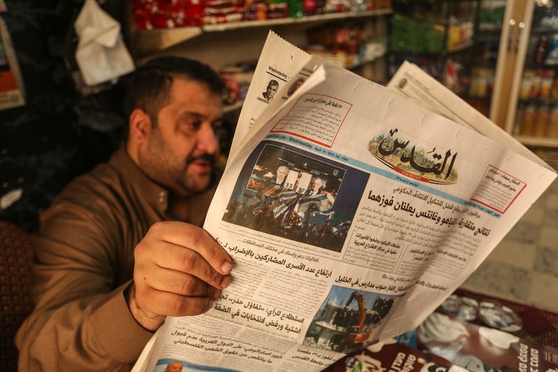 A man reads an Arabic-language newspaper in a shop