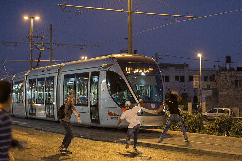 Youths throw stones at a tram