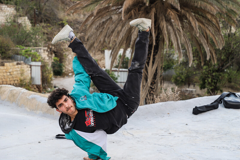 Man stands on one hand with legs pointed upwards in the air. 