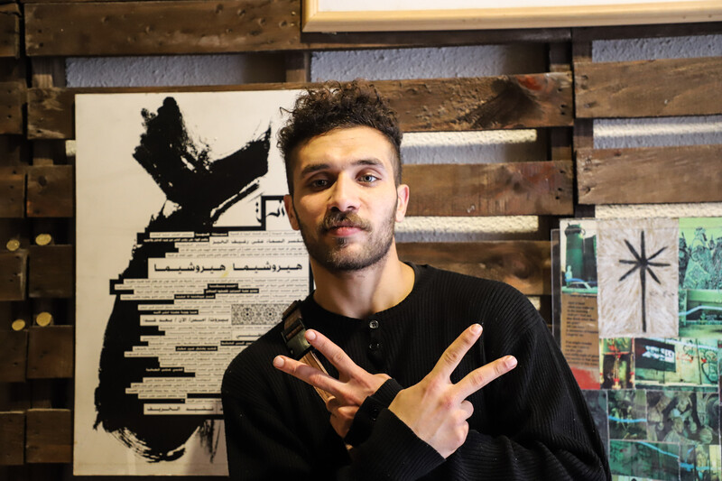 Man does peace sign with hands as he looks into the camera. 