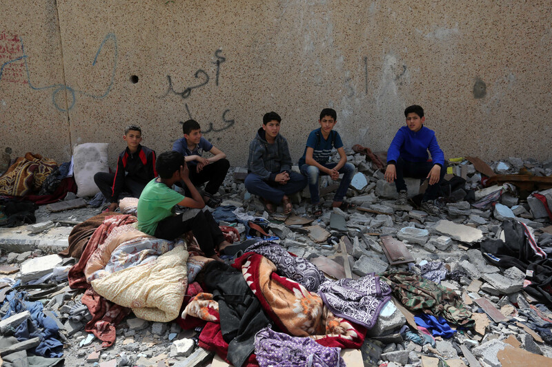 6 boys surrounded by rubble and damaged belongings