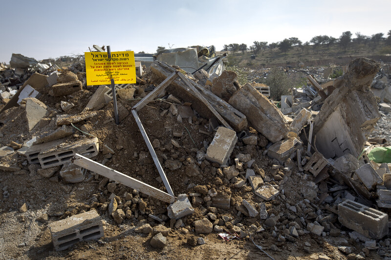 A warning sign in Hebrew and Arabic is posted on pile of rubble