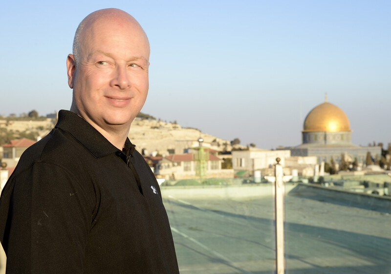 Man smiles with golden dome and other buildings behind him.