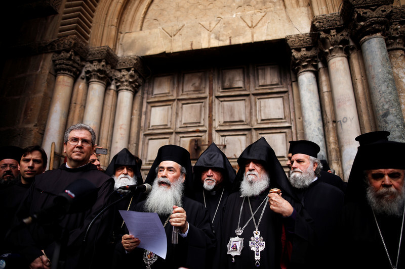 Men dressed in black robes stand side by side 