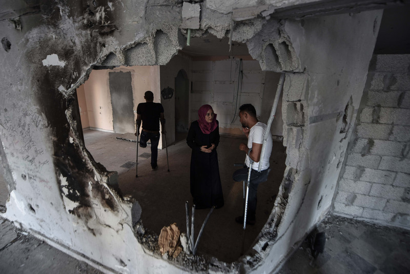Man and woman stand in front of bombed-out wall