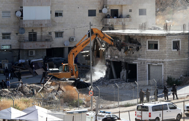 Bulldozer demolishing two-story building