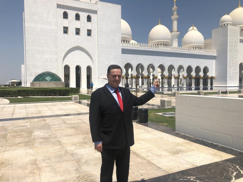 Man in suit points to mosque. 