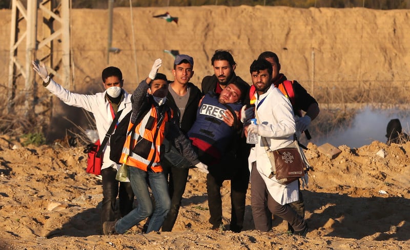 Six people, including medics, carry a man wounded in a protest.