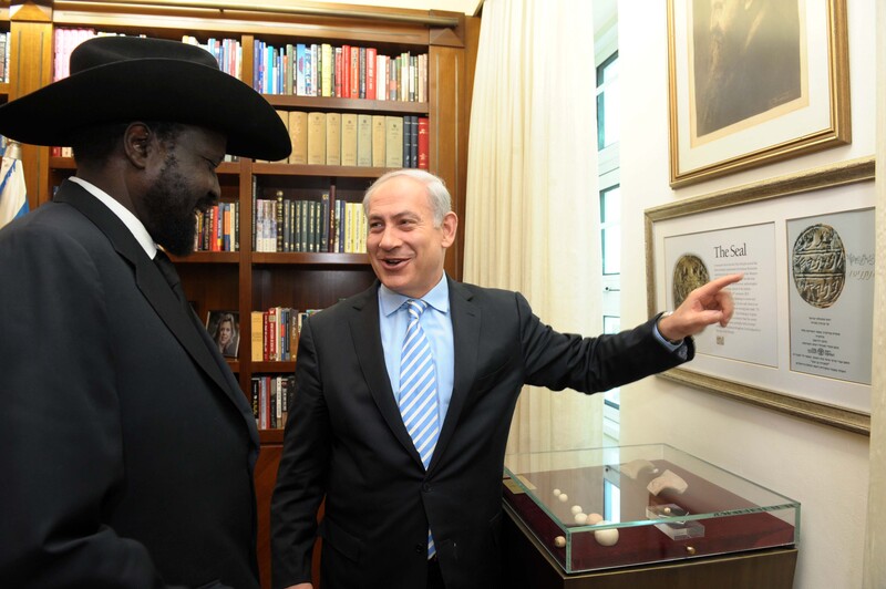 A man points to a framed picture as another looks on