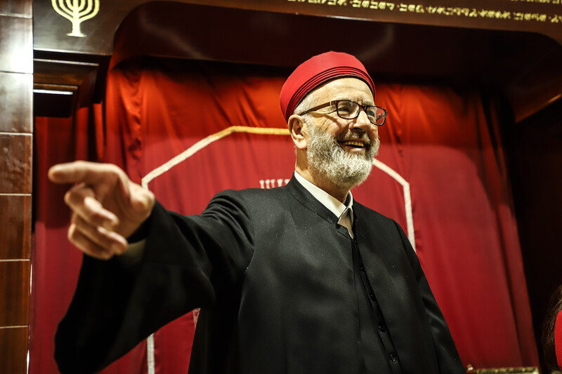 A man in religious garb gestures and smiles