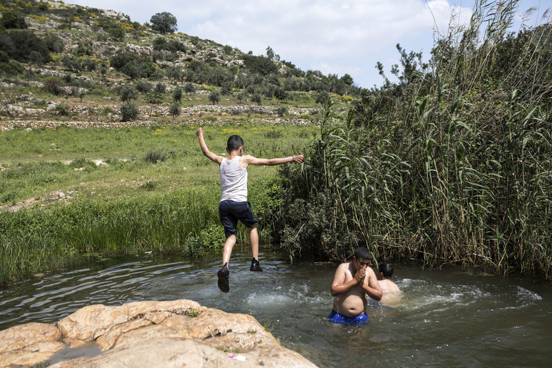 A Palestinian child jumps in a pool