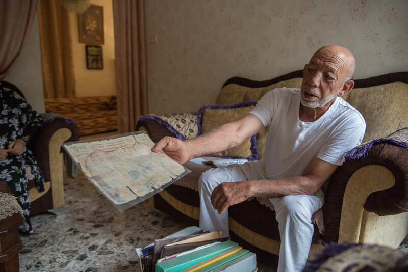 A man on a couch holds out a document