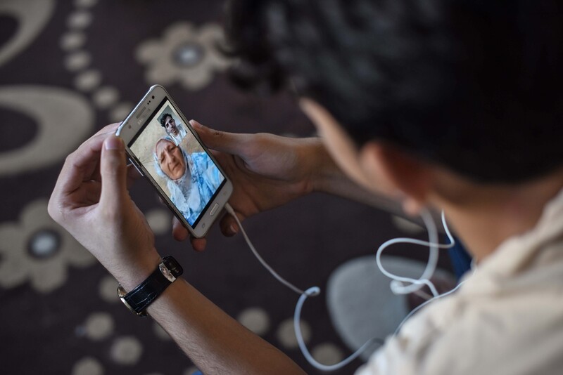 Young man holds phone showing image of woman