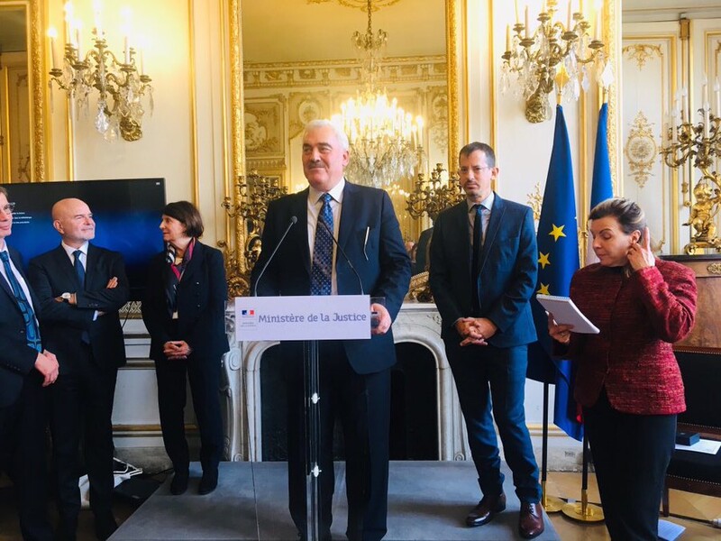 Man stands at podium with other people around him