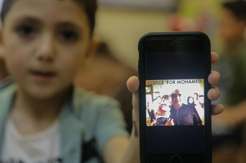 A boy holds a mobile phone with a picture of a man holding a baby