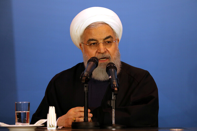 Seated man speaks at microphone