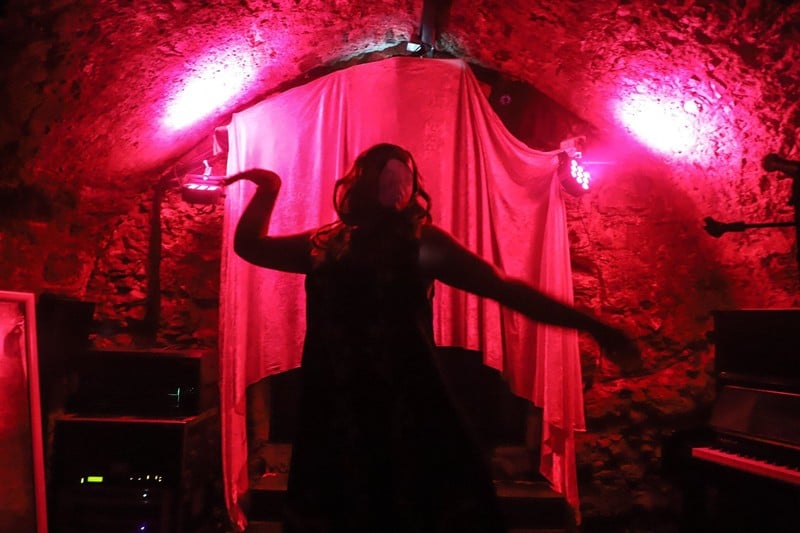 A dark silhouette against a red curtain of a person dancing