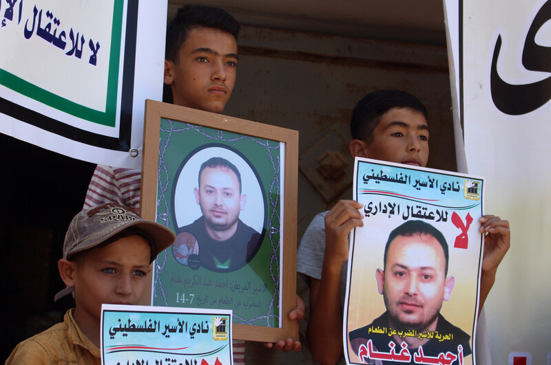 Three boys hold photos and banners