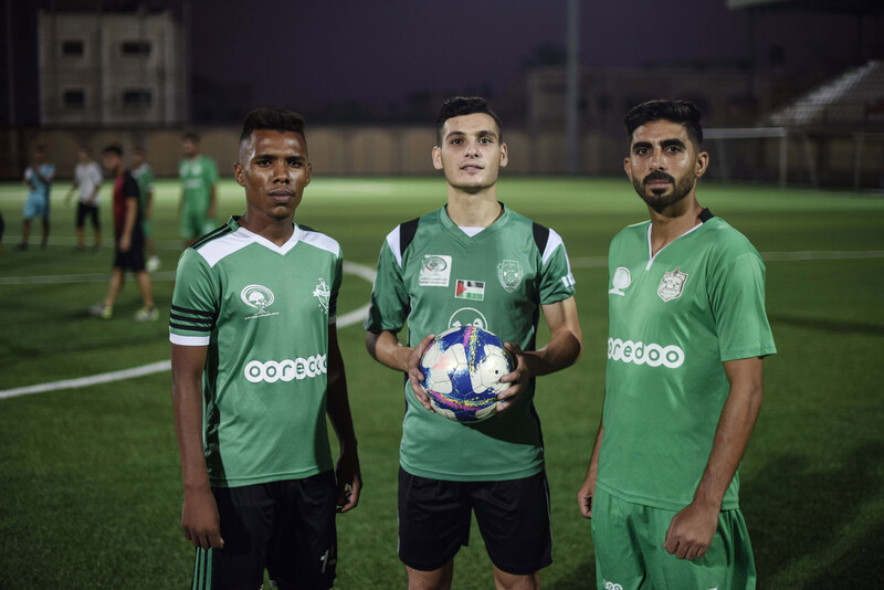 Three men in football uniforms look toward camera