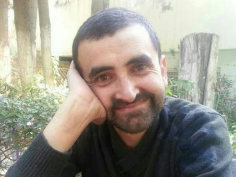 Man rests face on palm, smiles at the camera