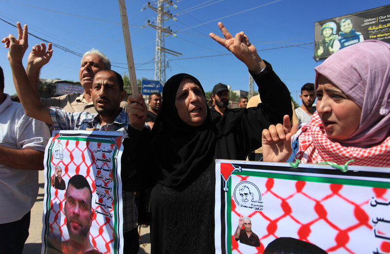 People hold banners, make peace sign with their hands