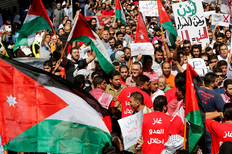 Crowd of dozens carry Jordanian flags, banners