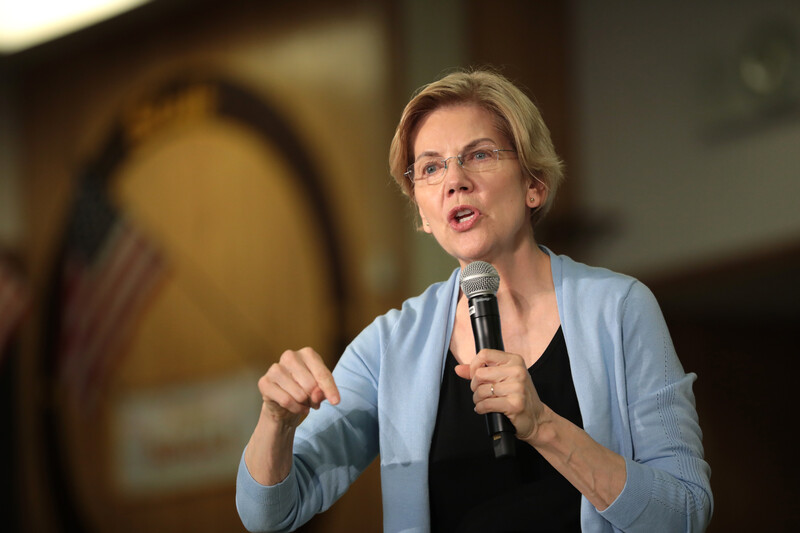 A woman holds a microphone and gestures