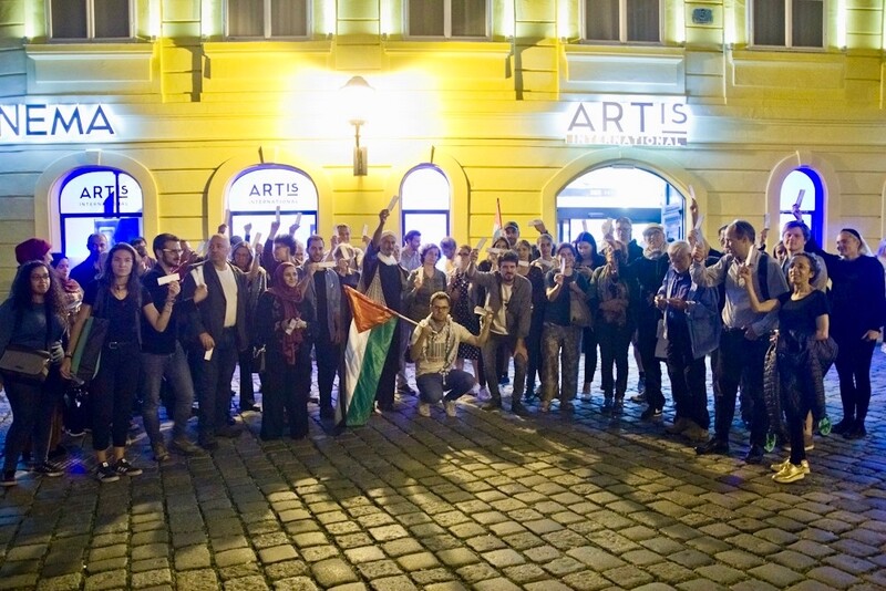 Large group of people stands in front of building