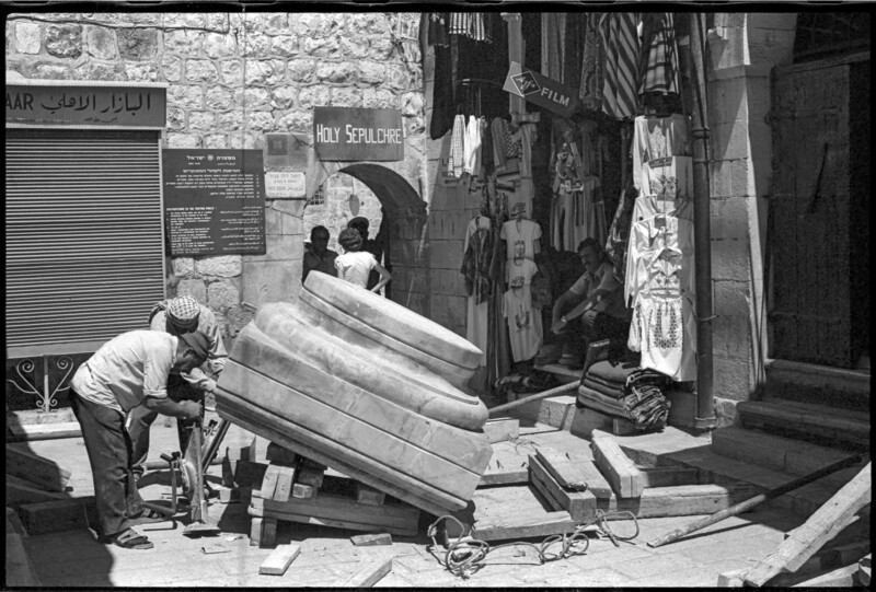 Men use jack to lift large object in front of Old City souvenir shop