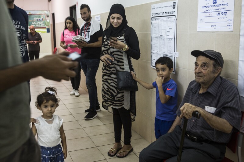 A group of people are waiting in a hallway