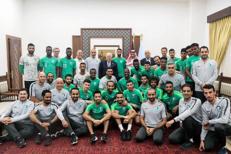 Men in football uniform pose with man in suit 