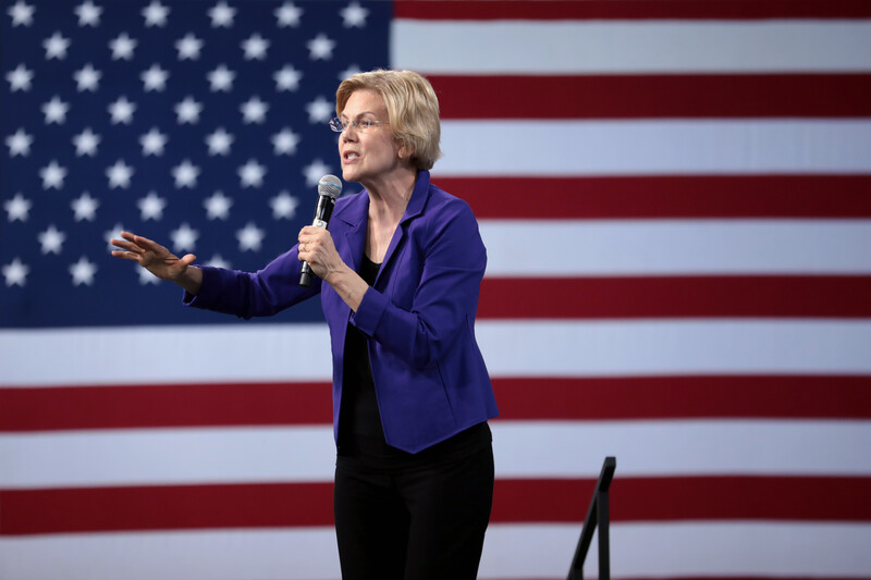 A woman with a microphone in front of American flag