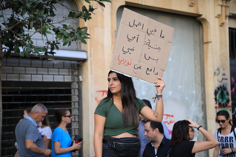 A woman holds up a sign with Arabic writing on it.