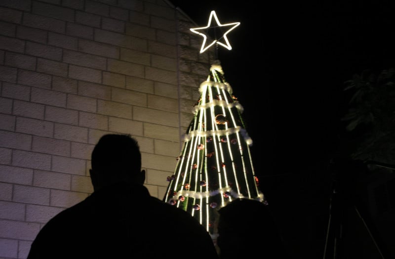 Silhouette of a man near a lit Christmas tree 
