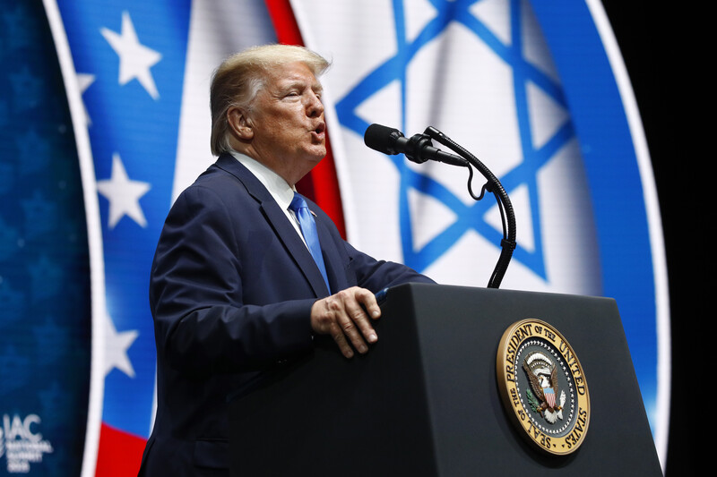 Man speaks at podium in front of Israeli and US flags