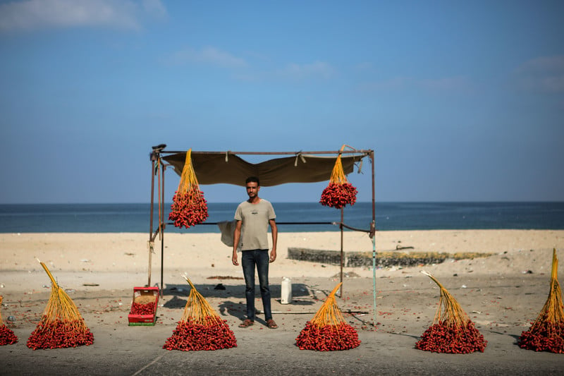 A man stands in a hut on the beach selling red dates.