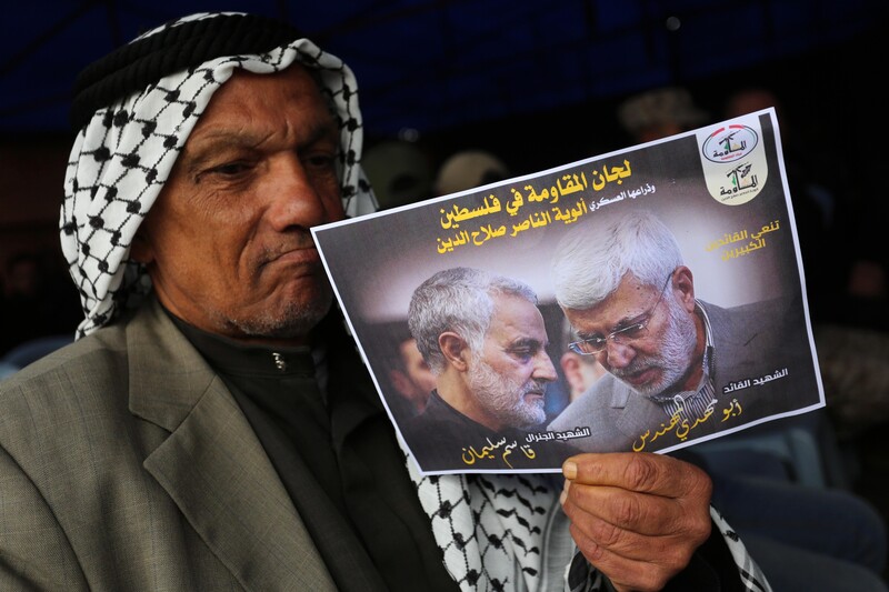 A man holds a picture of a slain Iranian general.