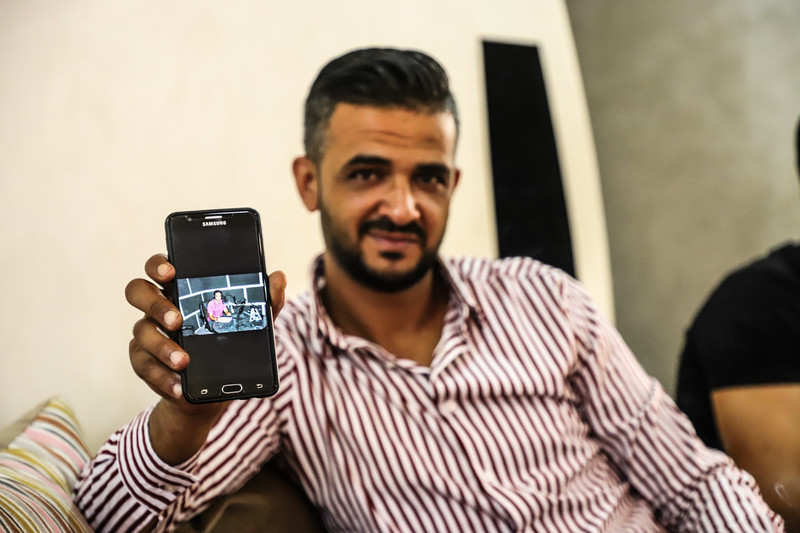 A man shows a picture of himself in a radio studio on a mobile phone