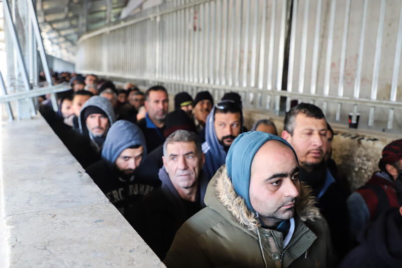 Men queue in a concrete walkway