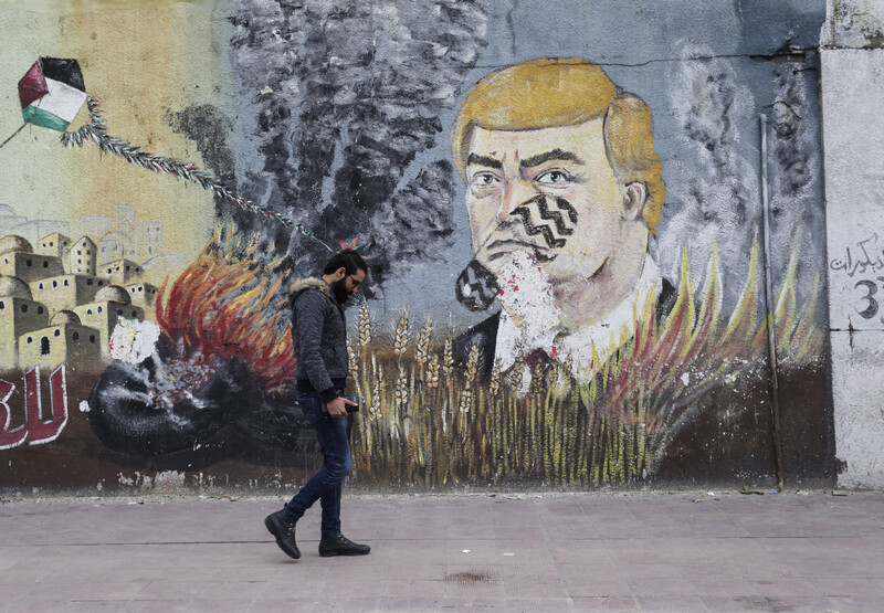 A man walks past a mural depicting US president Donald Trump with a footprint across his face