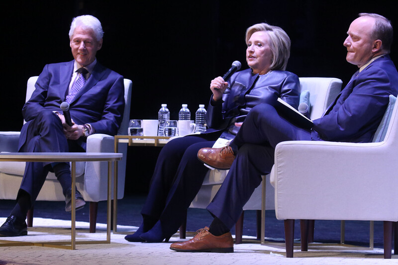 Three people talk on stage