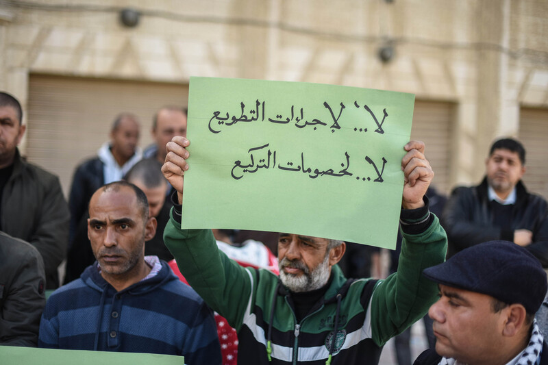 Palestinian men demonstrate and one holds sign