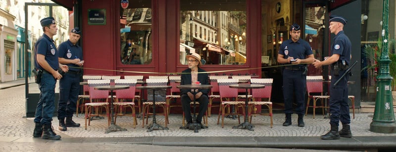Man sits at sidewalk cafe table behind police tape