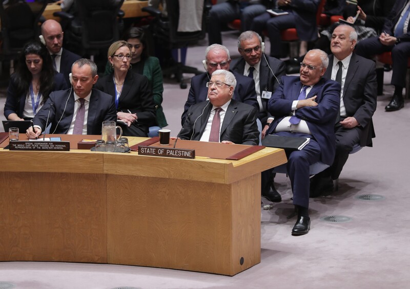 Several men, all in suits, sit behind a curved desk