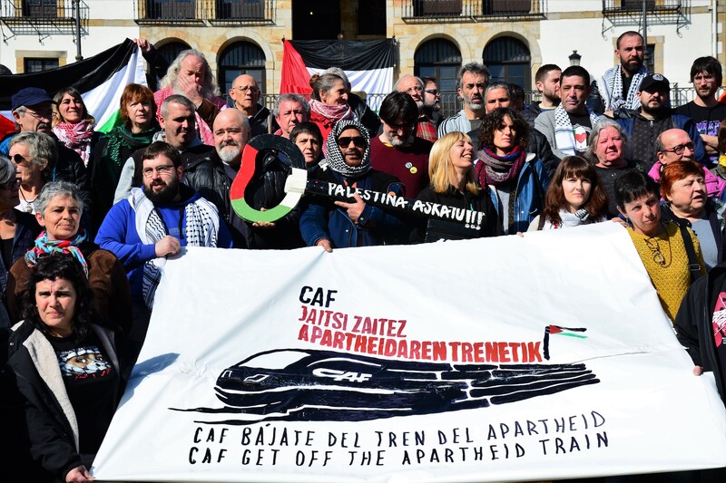 A large group of people holds a banner