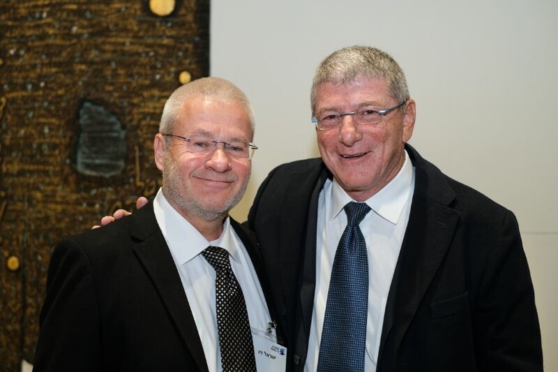 Two men stand together smiling