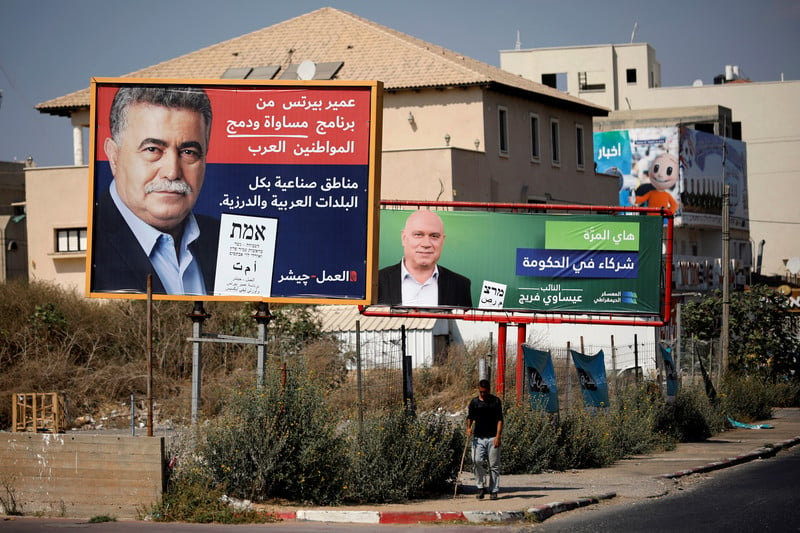 Two men are seen on two separate election banners in front of a house