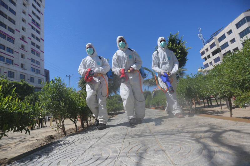 Three workers in uniform disinfect street